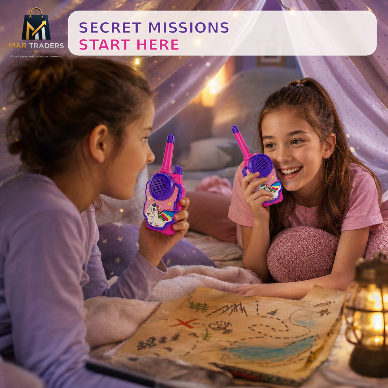 Two young girls sitting in a cozy bed or play tent, smiling and talking on colorful toy walkie-talkies. A treasure map and a lit lantern are on the table in front of them.