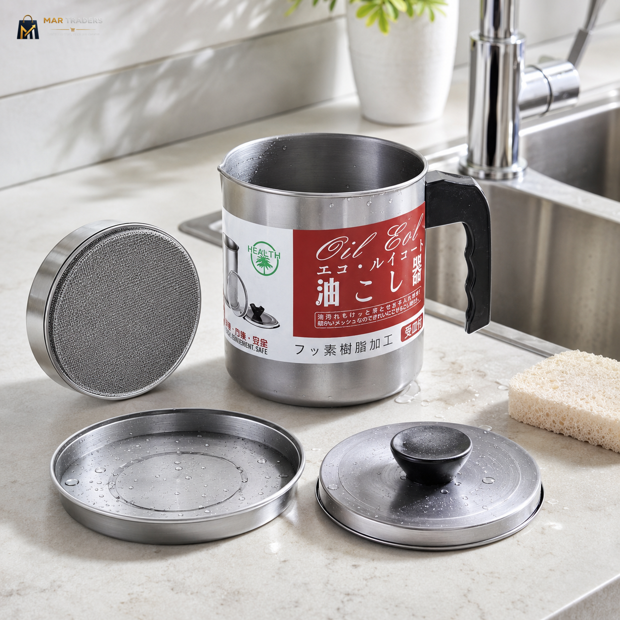 A stainless steel oil drain pan set with a handle, shown on a kitchen counter beside a sink. The set includes the main drain pan with a black handle, a round mesh filter, a drain tray, and a lid.