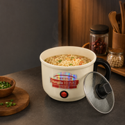 A white electric ramen cooker with a glass lid sits on a dark countertop, filled with cooked ramen noodles and vegetables. The cooker has a red power button and a colorful label reading Chungjila.