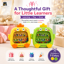 Two colorful magnetic bead toy birds, one yellow and one green, displayed on a light surface with a festive background of wrapped gifts and warm bokeh lights. The top features promotional text, and the bottom includes feature icons and an 'Available in 2 Colors' badge.