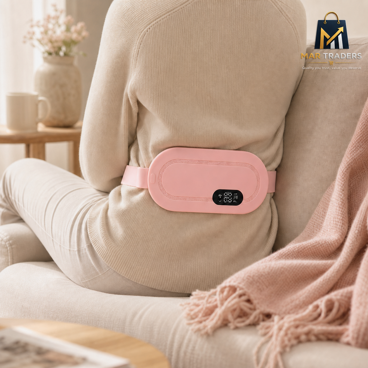 Person seated on a cream sofa wearing a MAR Traders pink heating pad across their lower back.